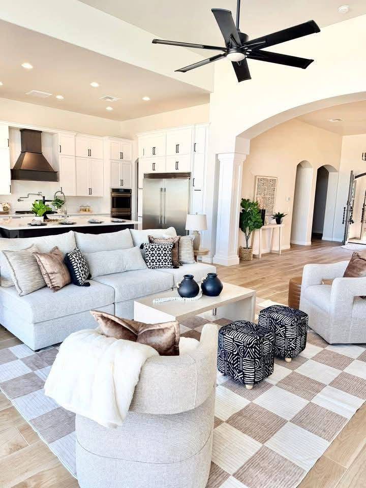 Great room open to the kitchen, staged with a checkerboard rug and boucle seating