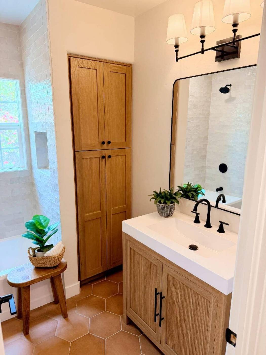 Guest bathroom staged with a wood vanity, black fixtures and framed mirror