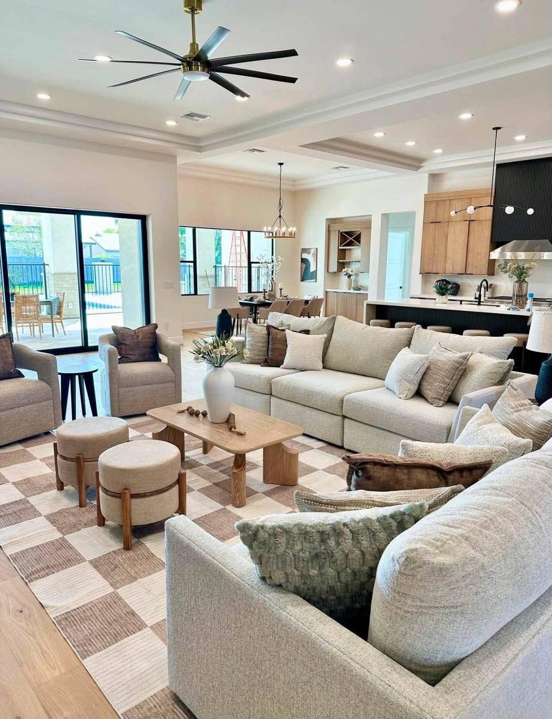 Coffered-ceiling great room staged with a long sectional and paired ottomans