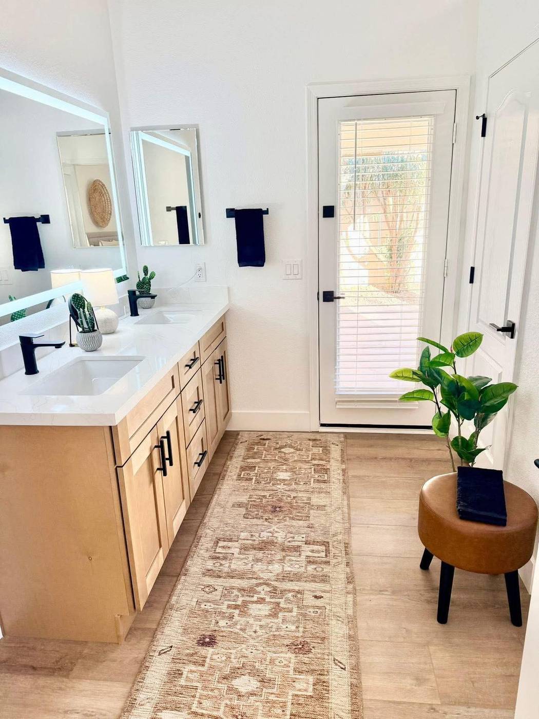 Double vanity bathroom staged with a runner rug, towels and a potted plant
